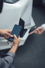 Inspecting Damage:  A hand points to a scratch on a white car, while another person checks the damage on their smartphone.