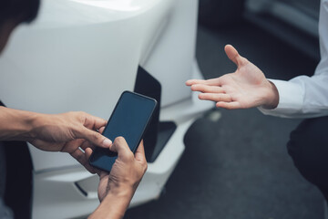 Mobile Car Insurance Claim:  A closeup shot showing a customer using his smartphone, seemingly reporting damage to his car to an insurance representative.