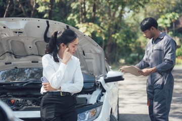 Roadside Assistance: A young woman looks concerned as a mechanic inspects her broken-down car,...