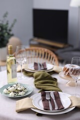Festive table setting with dishware, cutlery, glasses, desserts and wine indoors
