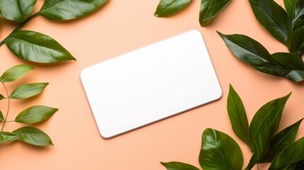 Naklejka premium White Blank Card Surrounded by Green Leaves on Orange Background