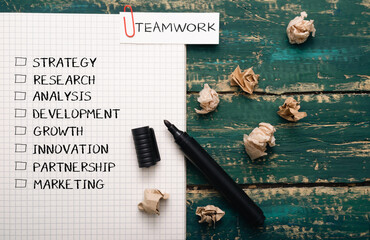 Piece of paper with a black marker on it with the word teamwork written in red