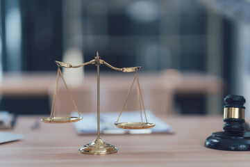 Scales of Justice: Golden scales of justice and a judge's gavel rest on a wooden desk, symbolizing...