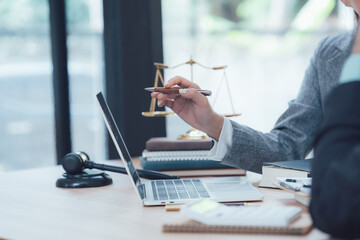 Lawyer Consulting Client: A lawyer sits at her desk, reviewing documents on her laptop, with a...