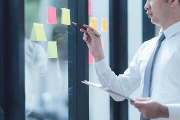 Strategic Planning Session: A focused businessman meticulously plans his strategy, writing on a...
