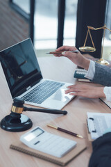 Legal Professional Working on Laptop: Close-up shot of a lawyer's hands using a laptop, with a gavel, scales of justice, and legal documents in the frame.