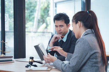 Legal Professionals Consulting: Two focused legal professionals, a man and a woman, collaborate intently over documents and a laptop.