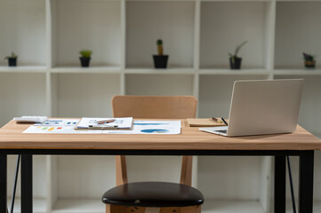 Minimalist Workspace:  A sleek modern desk with a laptop, notebook, and a few office supplies arranged neatly on a wood surface, invitingly empty and ready for the day's work.  