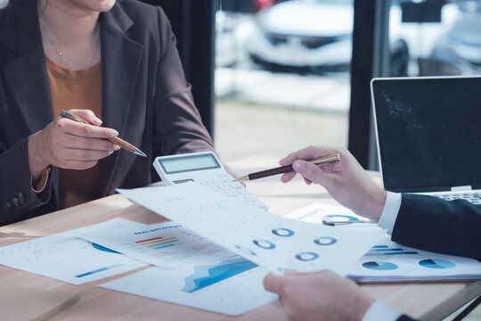 Data Analysis: A close-up shot of a financial advisor presenting financial data and discussing a plan with their client, highlighting a calculator, graphs and financial papers on the table.