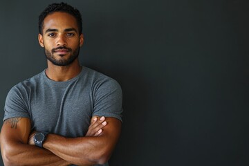 Obraz premium Calm man with arms crossed, looking directly at the camera with a slight smirk, against a dark gray background.
