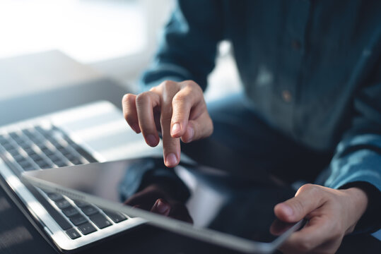 Close up, Woman using digital tablet with laptop computer on table at office. Business woman working on tablet, surfing the internet, searching the information, smart device, internet technology