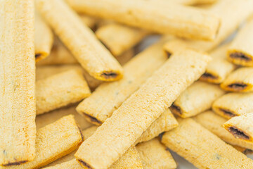 Close-up image of golden brown, crispy, slightly curved wafers scattered on a surface, possibly freshly baked or fried Neutral background