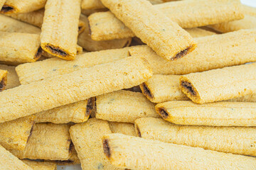 Image shows a stack of golden, textured rectangular biscuits or crackers, likely commercial brand