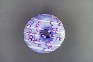 An individual doughnut with a purple glaze and blue dot decoration, showcasing a hole in the center