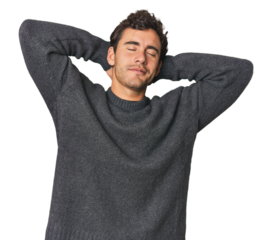 Young Hispanic man in studio feeling confident, with hands behind the head.