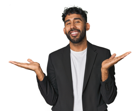 Hispanic businessman in suit in studio makes scale with arms, feels happy and confident.
