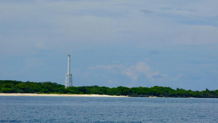 Lighthouse on a tropical island. View from the sea of ​​a lighthouse in the center of a tropical island. Apo Island.