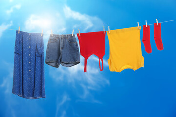 Different clothes drying on washing line against blue sky