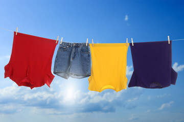 Different clothes drying on washing line against blue sky