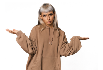 Young caucasian young woman in studio doubting and shrugging shoulders in questioning gesture.