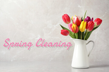 Spring cleaning. Beautiful tulips in vase on grey table