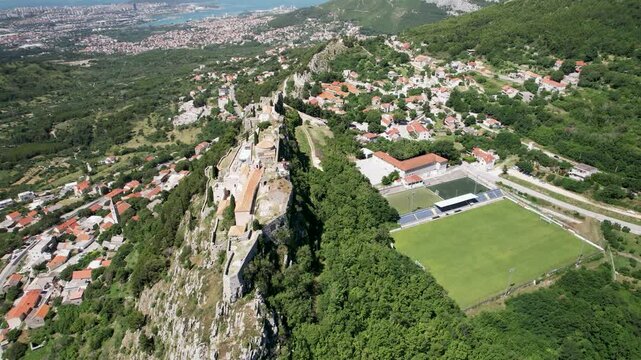 Orbit drone shot of Klis Fortress in the day with sunny weather, Croatia