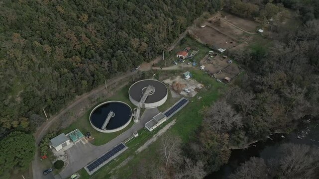 Industrial water treatment facility with circular clarifiers, solar panels, and river landscape near amelie les bains palalda, revealing advanced environmental infrastructure in southern france