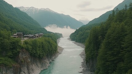 Aerial view of a river flowing through a lush green valley surrounded by mountains and mist.