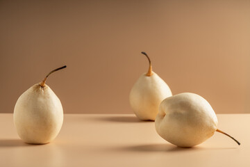 Three Asian ripe yellow pears lie on the table on a brownish background.