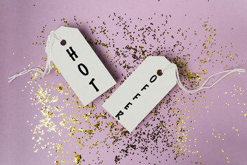 Two tags with the word HOT Offer written on them are on top of a pile of glitter