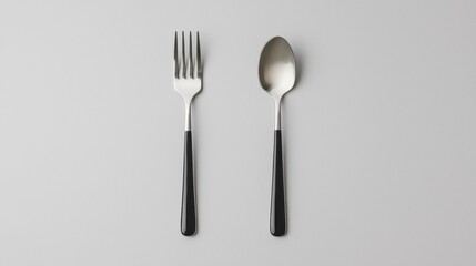 A fork and spoon are placed side by side on a neutral background, showcasing simple yet elegant tableware design.
