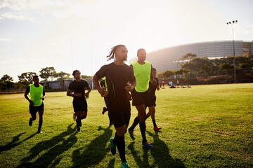 Fototapeta premium Sports, running and men with training for rugby, competition game or practice with warm up for match. Stadium, people and group of players for fitness, stretching or club team for tournament by flare