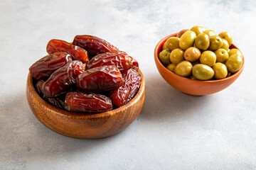 Dates fruit with a bowl of green olive on bright background 