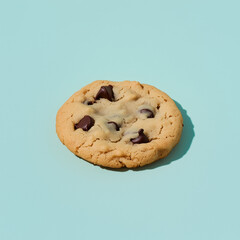 A chocolate chip cookie with melted chocolate on a soft light blue background 