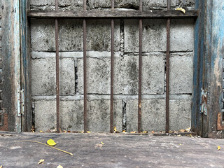 Old wooden window with metal bars and concrete wall