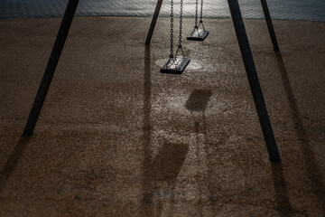 Lonely empty swings for children in an empty playground. Sad empty swings with no people on it....