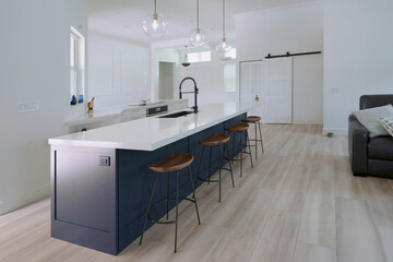 Interior modern farmhouse kitchen with blue island cabinets and white quartz countertop designed with contemporary finishes and wood floor tiles