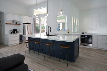 Interior modern farmhouse kitchen with blue island cabinets and white quartz countertop designed with contemporary finishes and wood floor tiles