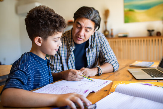 Father helping son with homework at kitchen table