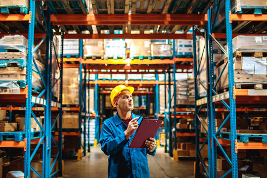 Warehouse supervisor inspecting inventory with clipboard in storage facility