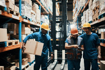 Warehouse workers collaborating and carrying packages in logistics center
