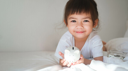 Cute child with a joyful smile holding a toy in a cozy bedroom setting, showcasing innocence and...