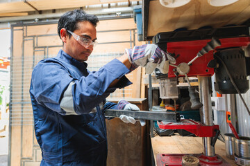 Latin worker drilling metal in workshop using bench drill press