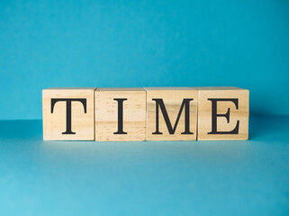 The word time is written in wooden blocks on a blue background