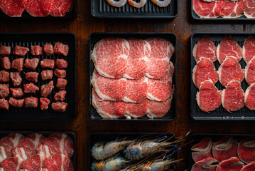 Assorted Raw Meats Arranged Neatly in Plastic Trays on Wooden Table