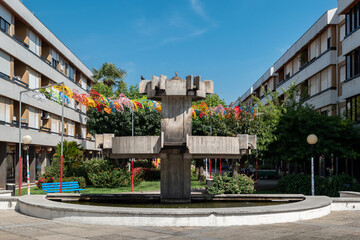 Obraz premium Fonte de concreto numa praça pública rodeado por decorações coloridas e vegetação em Portugal