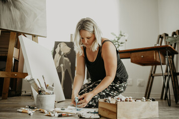 Paint, canvas and girl on floor at studio for artwork with project for passion with colour at...