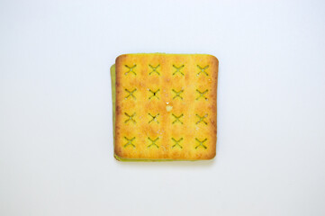 A close-up of a square biscuit with a green filling, isolated on a white background