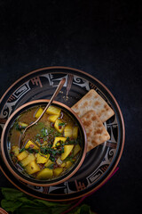 Vegan potato and beet greens soup served in ceramic bowl, along with crackers