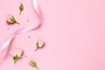 Beautiful composition with pink roses and silk ribbon on color background